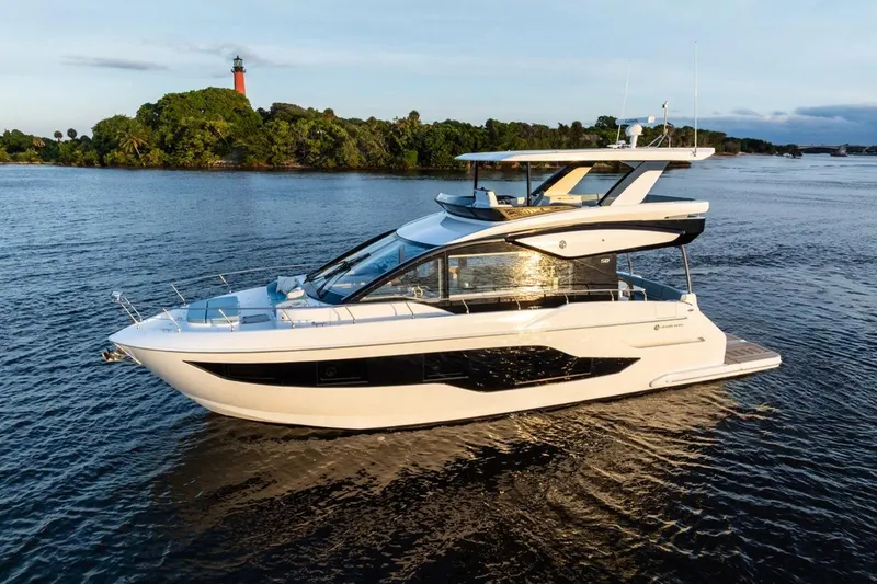 Slide: The Image of 2026 Cruisers Yachts 50 Fly on serene water with lush greenery backdrop. - 28