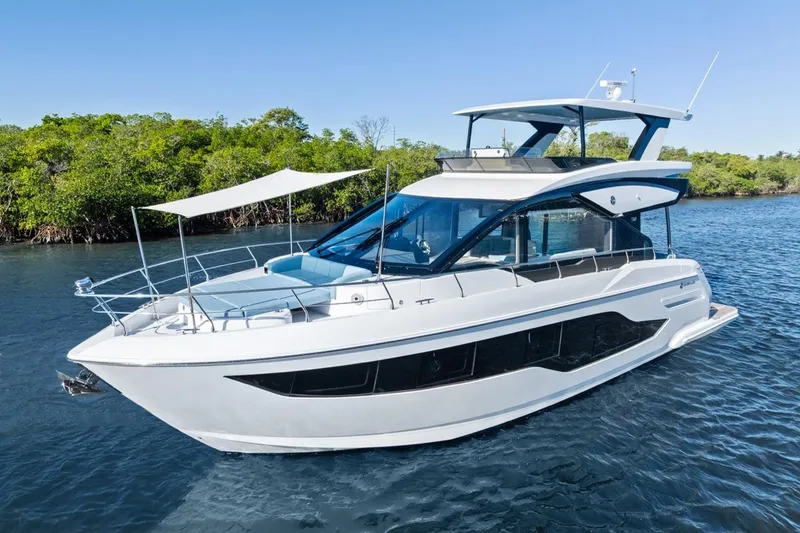 Slide: The Image of 2026 Cruisers Yachts 50 Fly luxury yacht on serene water, surrounded by lush greenery. - 3