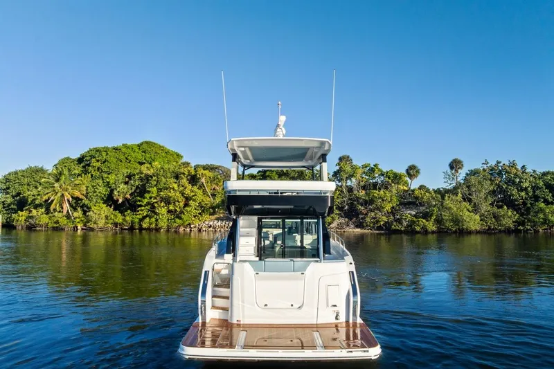 Slide: The Image of 2026 Cruisers Yachts 50 Fly on serene water with lush green backdrop. - 31