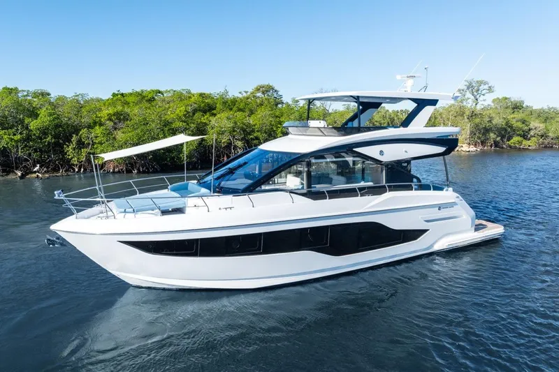 Slide: The Image of 2026 Cruisers Yachts 50 Fly luxury yacht on serene water, surrounded by lush greenery. - 4