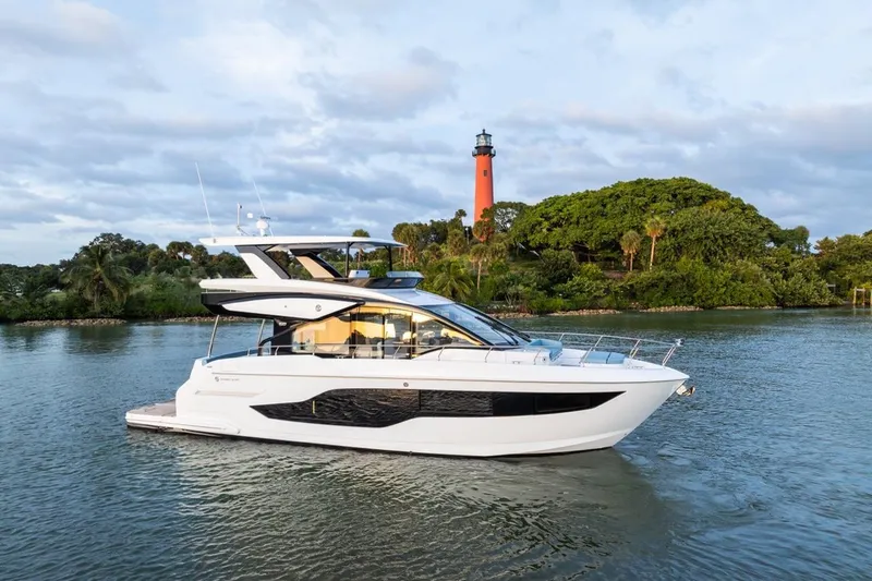 Slide: The Image of 2026 Cruisers Yachts 50 Fly on water near a lighthouse and lush greenery. - 42