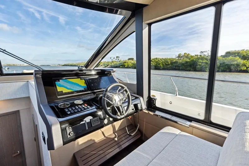 Slide: The Image of Interior helm of 2026 Cruisers Yachts 50 Fly with navigation screens and river view. - 47