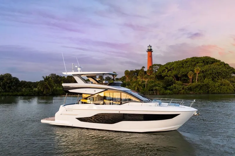 Slide: The Image of 2026 Cruisers Yachts 50 Fly on serene water with scenic lighthouse backdrop. - 6