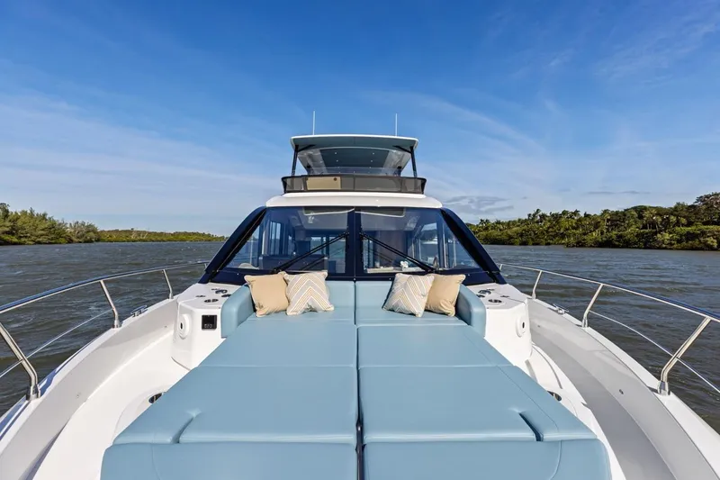 Slide: The Image of 2026 Cruisers Yachts 50 Fly on water, featuring spacious deck with cushions. - 64