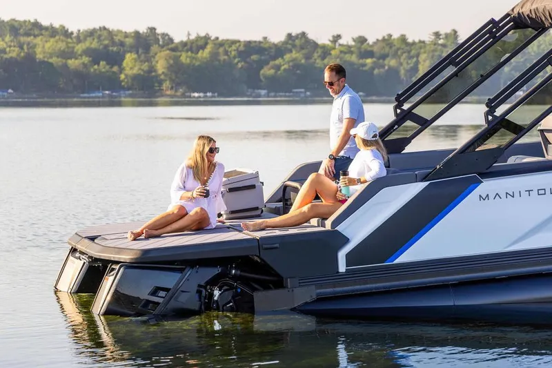 Slide: The Image of Manufacturer Provided Image: Manitou Explore Dual Engine 2025 on a serene lake with three people. - 2