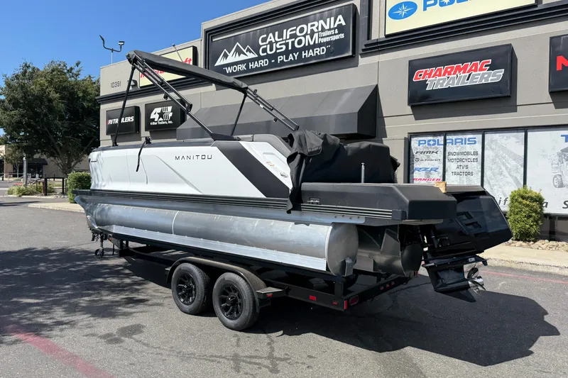 Slide: The Image of 2025 Manitou Cruise pontoon boat on trailer outside dealership. - 2
