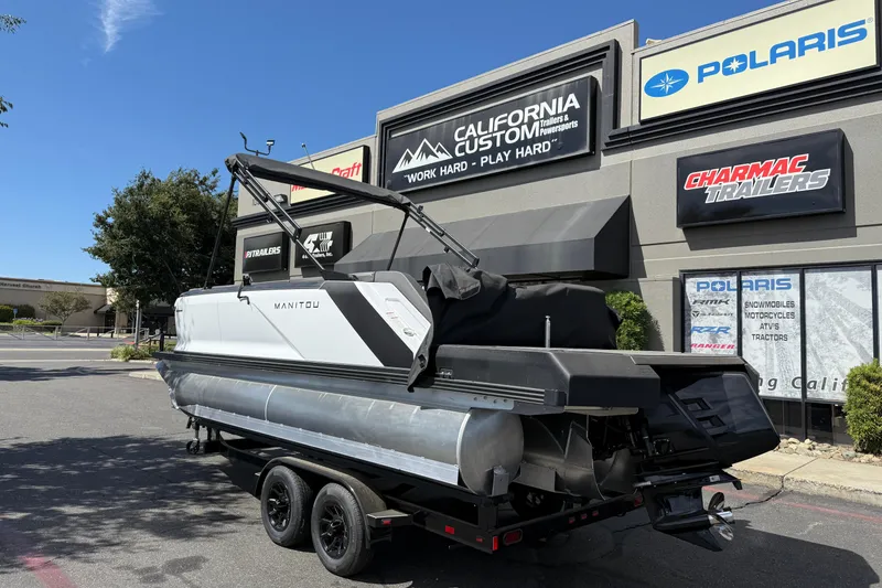 Slide: The Image of 2025 Manitou Cruise pontoon boat on trailer outside California Custom store. - 3