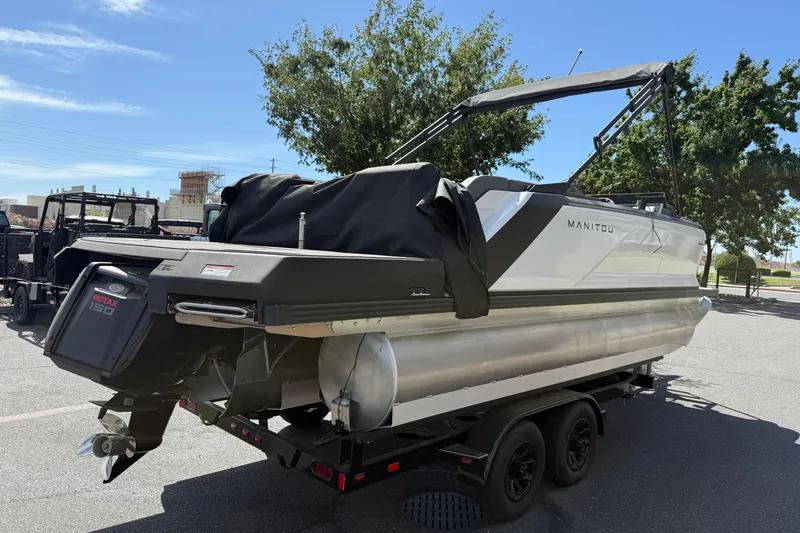 Slide: The Image of 2025 Manitou Cruise pontoon boat on trailer, featuring Rotax 150 engine, parked outdoors. - 5