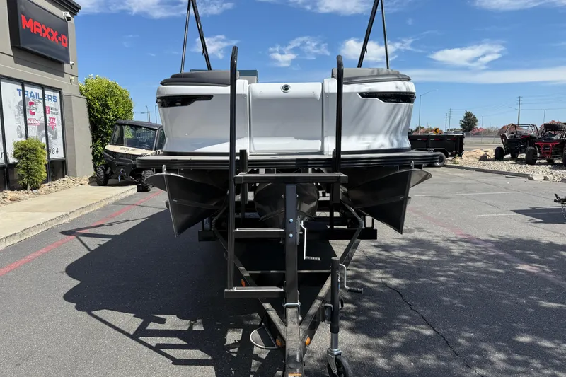 Slide: The Image of 2025 Manitou Cruise pontoon boat on trailer in parking lot, sunny day. - 7