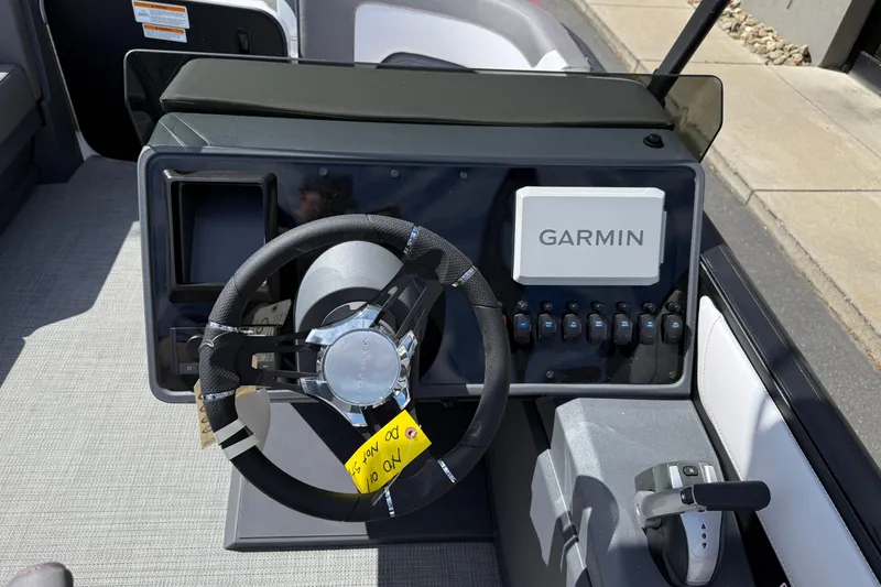 Slide: The Image of 2025 Manitou Cruise boat dashboard with Garmin navigation system and steering wheel. - 8