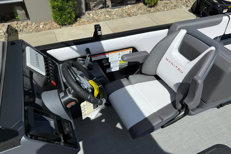 Slide: The Image of 2025 Manitou Cruise boat cockpit with Garmin navigation and branded seating. - 9