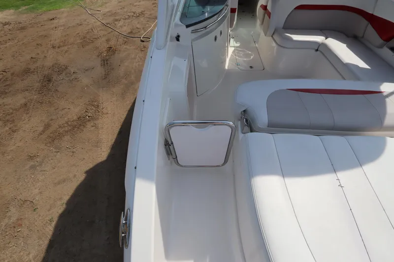 Slide: The Image of 2016 Chaparral 287 SSX boat interior with white and red seating, docked on sandy ground. - 15