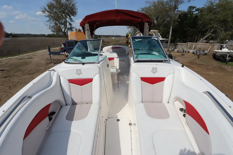 Slide: The Image of 2016 Chaparral 287 SSX boat interior with white and red seating, parked outdoors. - 46