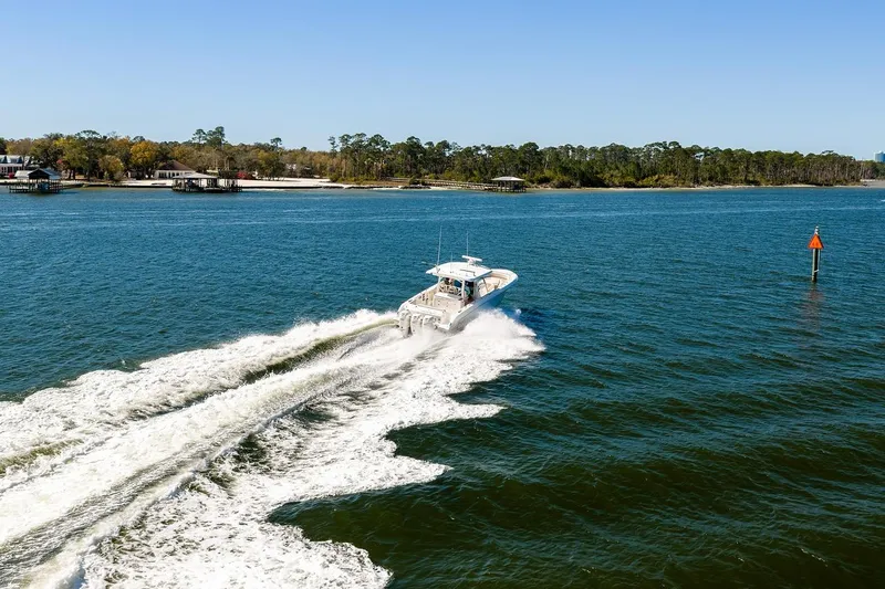 Slide: The Image of Boston Whaler 380 Outrage 2018 cruising on a scenic lake with forested shoreline. - 14