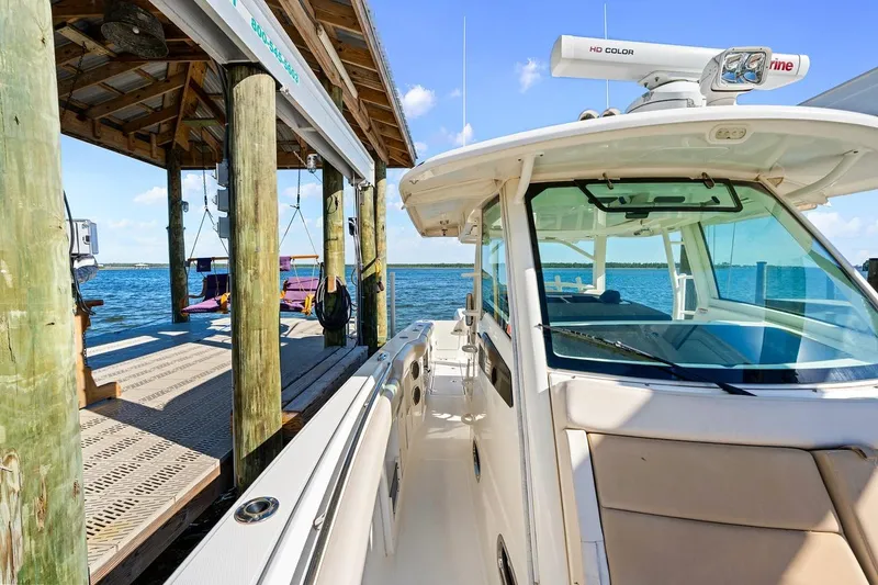 Slide: The Image of 2018 Boston Whaler 380 Outrage docked by a scenic waterfront with a wooden pier. - 28