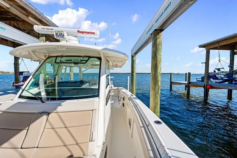 Slide: The Image of 2018 Boston Whaler 380 Outrage docked by a serene waterfront under a clear blue sky. - 29