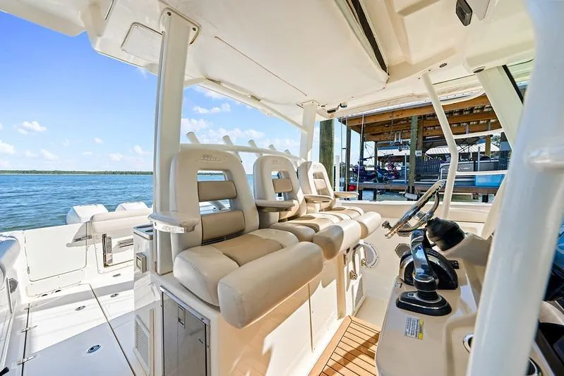 Slide: The Image of 2018 Boston Whaler 380 Outrage interior with helm and seating, docked by the water. - 35