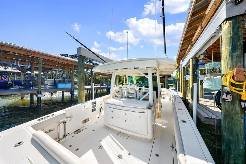 Slide: The Image of 2018 Boston Whaler 380 Outrage docked, showcasing spacious deck and seating under clear blue sky. - 40