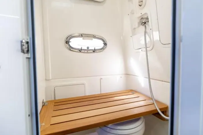 Slide: The Image of 2018 Boston Whaler 380 Outrage bathroom with wooden bench and showerhead. - 5