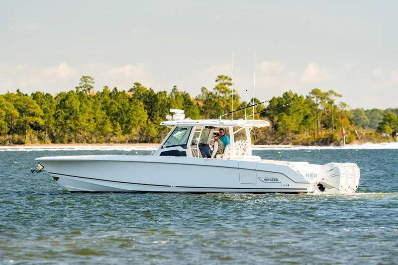 Slide: The Image of 2018 Boston Whaler 380 Outrage cruising on a scenic lake with forested shoreline. - 52