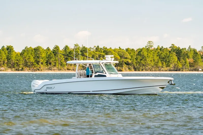 Slide: The Image of 2018 Boston Whaler 380 Outrage cruising on a scenic lake with forested shoreline. - 56
