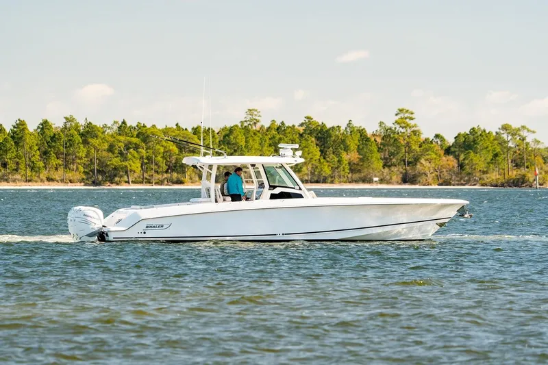 Slide: The Image of 2018 Boston Whaler 380 Outrage cruising on a scenic lake with forested shoreline. - 57