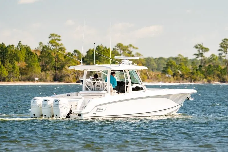 Slide: The Image of 2018 Boston Whaler 380 Outrage cruising on a scenic lake with trees in the background. - 58