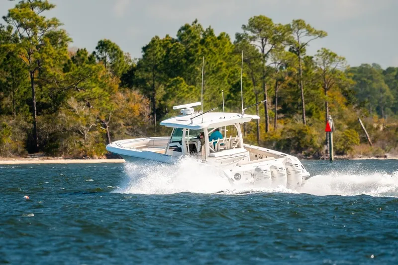 Slide: The Image of 2018 Boston Whaler 380 Outrage cruising on a scenic waterway with lush greenery. - 60