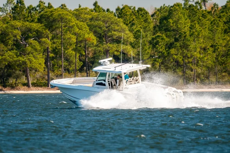 Slide: The Image of 2018 Boston Whaler 380 Outrage cruising on a scenic lake with lush forest backdrop. - 61