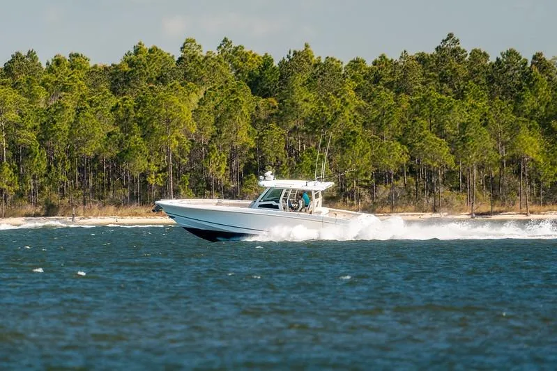 Slide: The Image of 2018 Boston Whaler 380 Outrage cruising on a scenic lake with forested shoreline. - 62