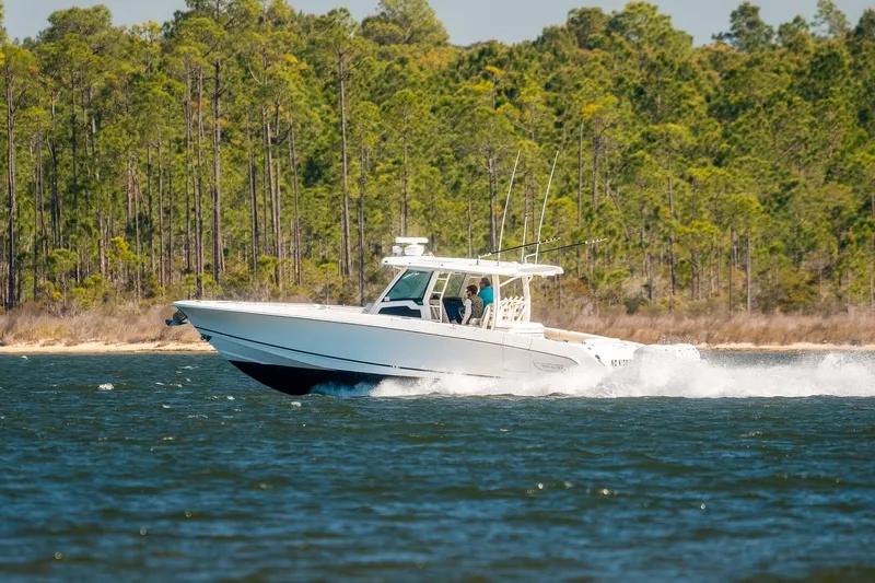 Slide: The Image of 2018 Boston Whaler 380 Outrage cruising on a lake with forested shoreline. - 63