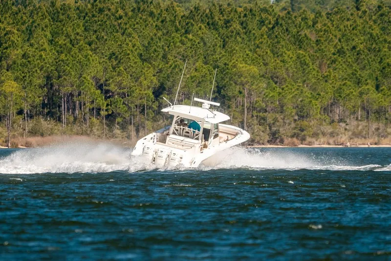 Slide: The Image of 2018 Boston Whaler 380 Outrage cruising on a lake with forested shoreline. - 64