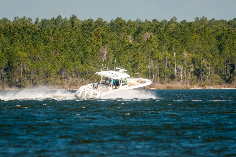 Slide: The Image of 2018 Boston Whaler 380 Outrage cruising on a lake with forested shoreline. - 65