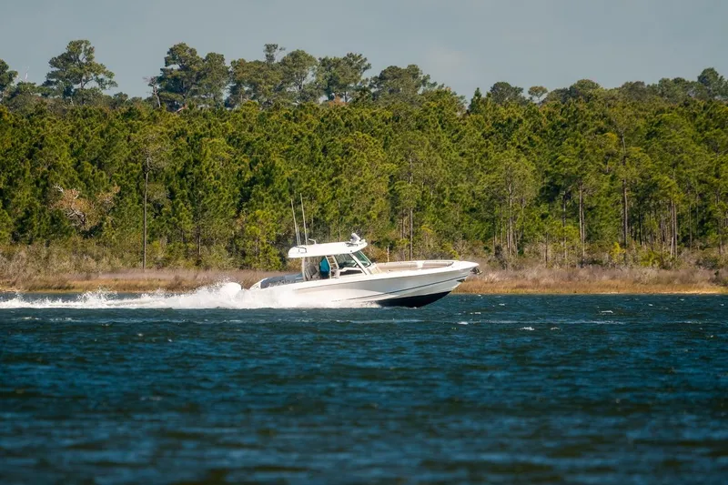 Slide: The Image of 2018 Boston Whaler 380 Outrage cruising on a lake with forested shoreline. - 66