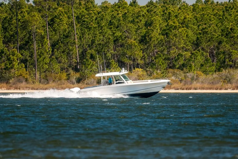 Slide: The Image of 2018 Boston Whaler 380 Outrage cruising on a scenic lake with forest backdrop. - 67