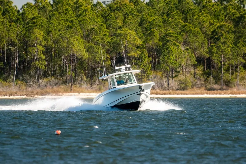 Slide: The Image of 2018 Boston Whaler 380 Outrage cruising on a lake with forested shoreline. - 70