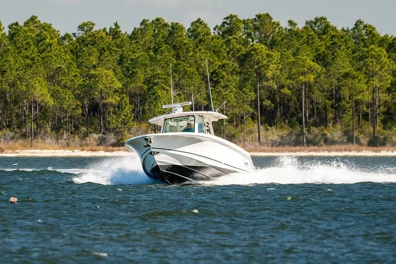 Slide: The Image of 2018 Boston Whaler 380 Outrage cruising on a lake with forested shoreline. - 71
