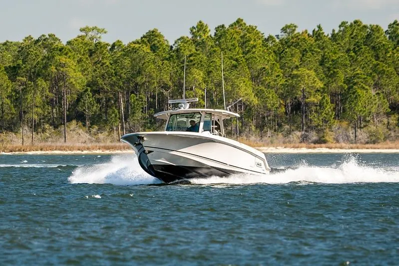 Slide: The Image of 2018 Boston Whaler 380 Outrage cruising on a lake with forested shoreline. - 72