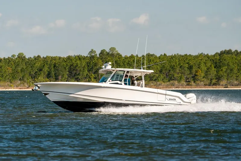 Slide: The Image of 2018 Boston Whaler 380 Outrage cruising on a lake with forested shoreline. - 74
