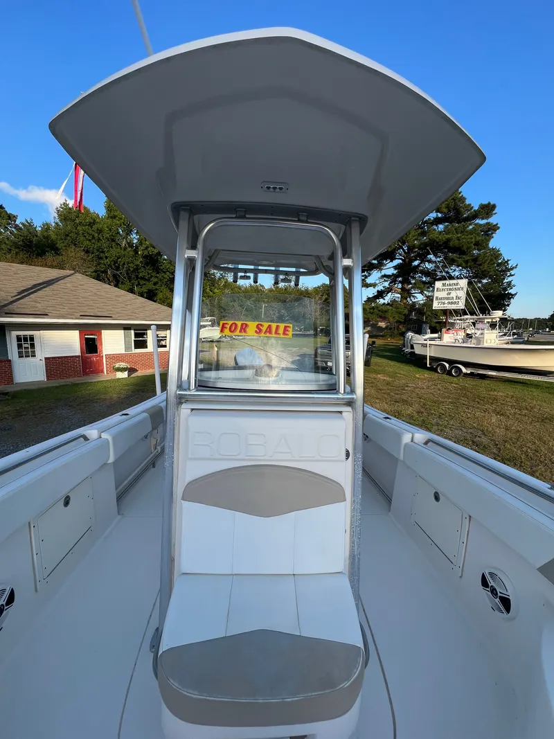 Slide: The Image of A 2020 Robalo R242 Center Console boat with a 'For Sale' sign, parked outdoors. - 20