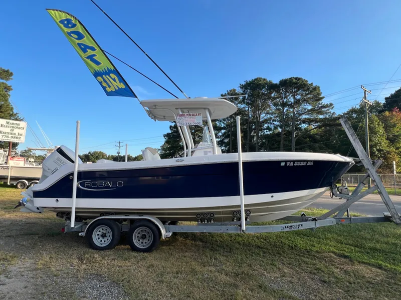 Slide: The Image of A 2020 Robalo R242 Center Console boat on a trailer, featuring a blue hull and T-top. - 13