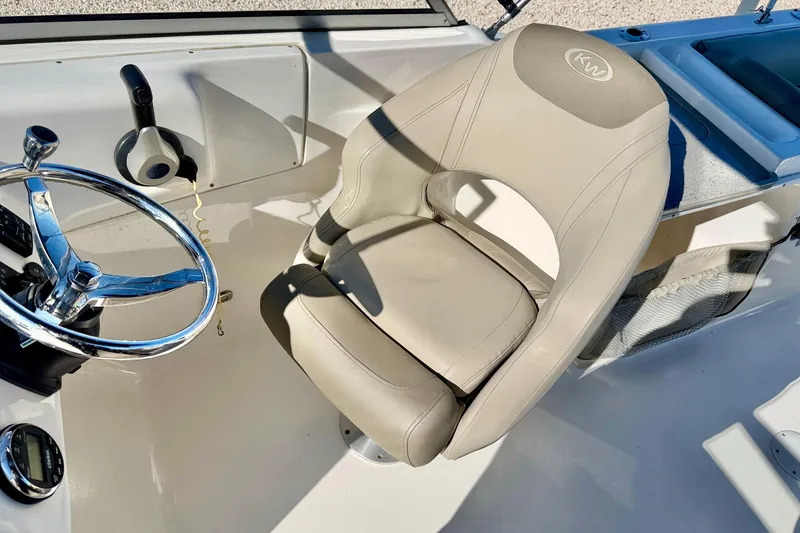 Slide: The Image of 2023 Key West 239 DFS boat cockpit with steering wheel and beige captain's chair. - 13