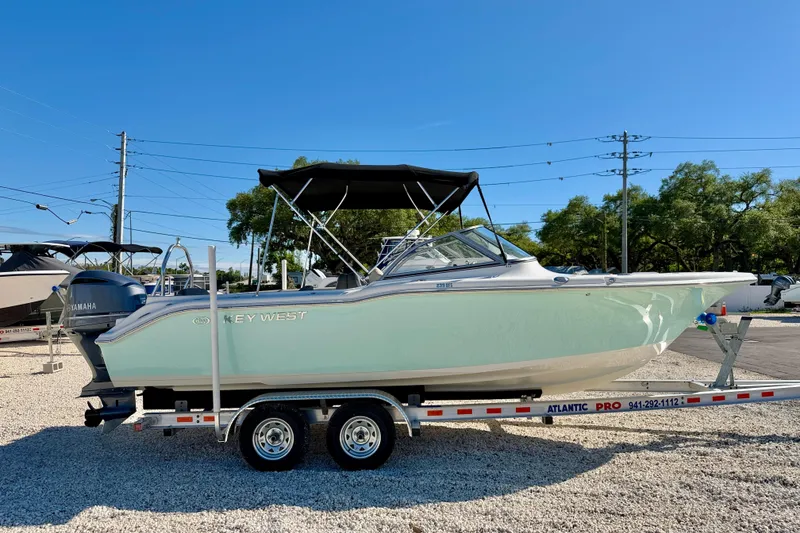 Slide: The Image of 2023 Key West 239 DFS boat on trailer, parked outdoors under clear blue sky. - 4