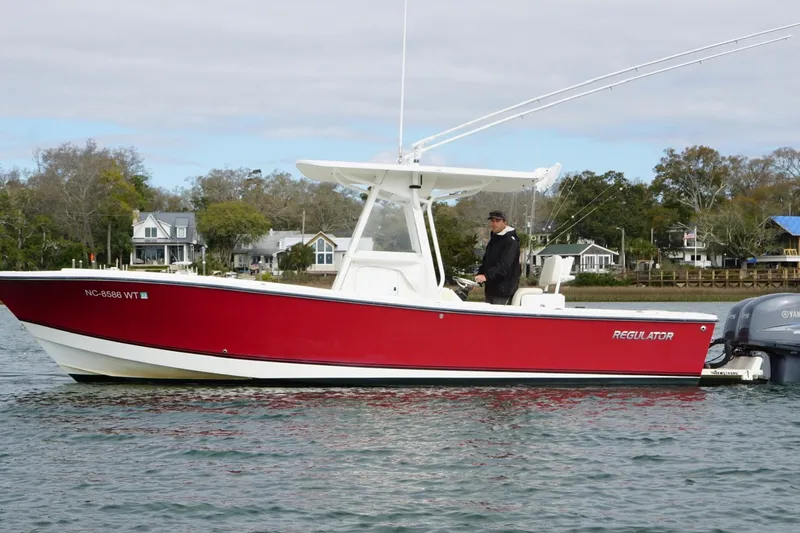 The Image of 2003 Regulator 26 Forward Seating boat on water, red hull, scenic background. - 1