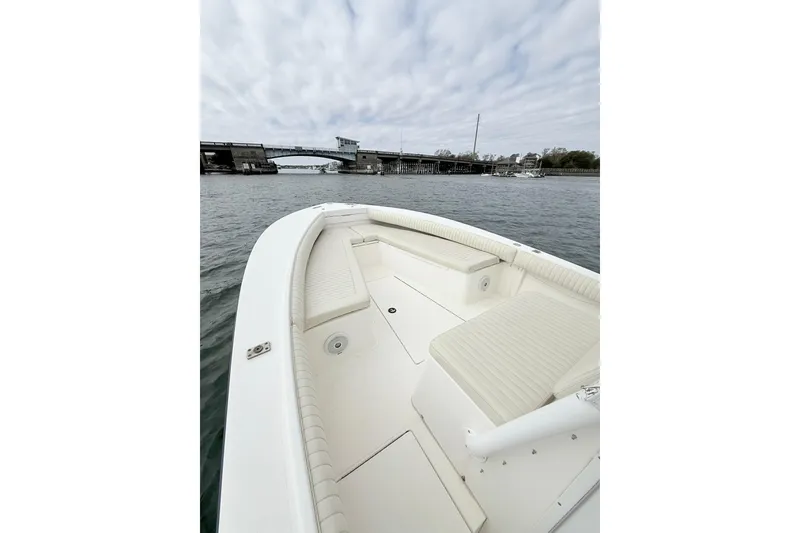 Slide: The Image of 2003 Regulator 26 Forward Seating boat on water near a bridge under cloudy sky. - 14