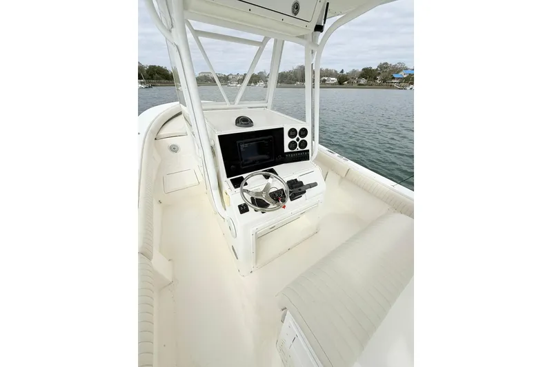 Slide: The Image of 2003 Regulator 26 Forward Seating boat interior with steering console and seating, on calm water. - 16