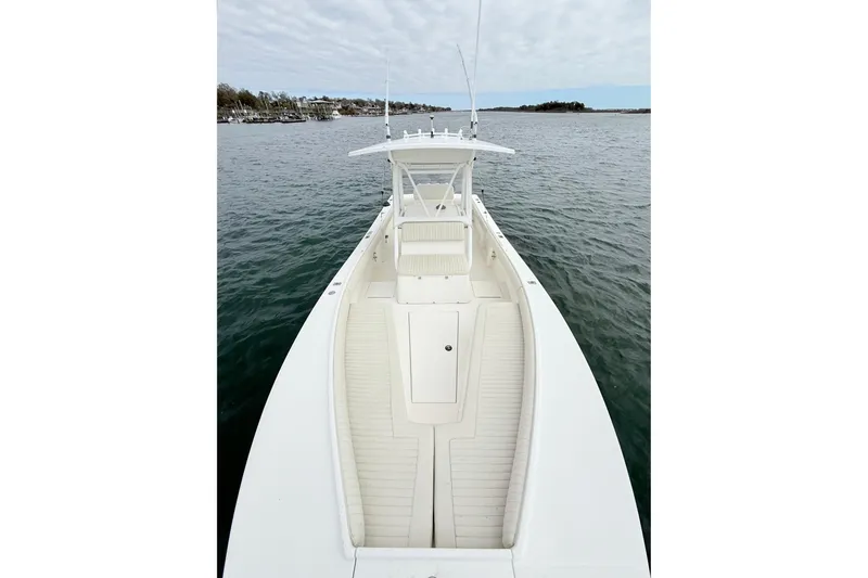 Slide: The Image of 2003 Regulator 26 Forward Seating boat on calm water, showcasing spacious deck and seating. - 17
