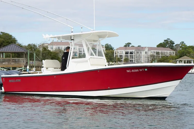 Slide: The Image of Red 2003 Regulator 26 Forward Seating boat on water near docks and buildings. - 5