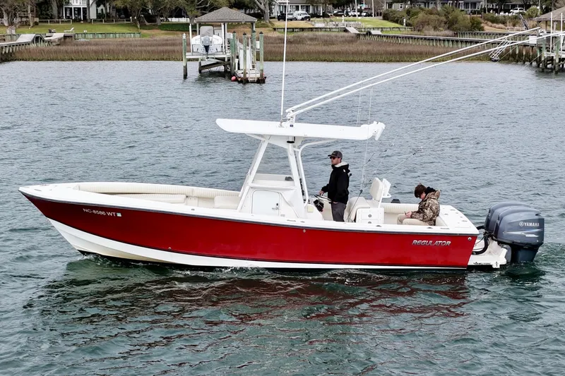 Slide: The Image of 2003 Regulator 26 Forward Seating boat on water, red hull, Yamaha engine, two people onboard. - 8