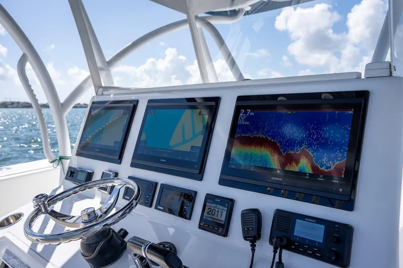 Slide: The Image of Control panel of a 2016 SeaHunter 45 boat with navigation screens and steering wheel. - 16